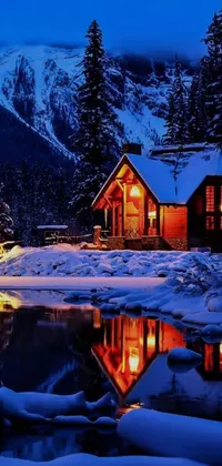 Get immersed in the beauty of this phone live wallpaper depicting a cozy cabin surrounded by snow-capped trees on a serene night