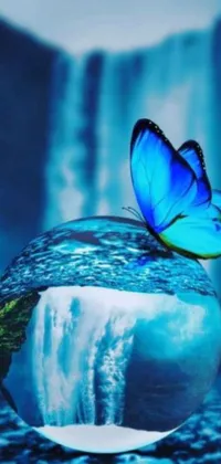 This phone live wallpaper features a stunning digital art of a blue butterfly resting atop a glass ball with cascading waterfalls and crypto elements