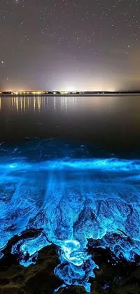 This stunning phone live wallpaper showcases a breathtaking view of the ocean at night with glowing caustics on the water that give it a realistic quality