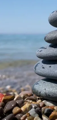 This phone live wallpaper showcases a serene beach vibe with a stack of rocks, reflecting a modern touch through a YouTube video screenshot