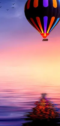 Experience the beauty of nature and fine art with this vibrant phone live wallpaper of a colorful hot air balloon flying over a serene body of water