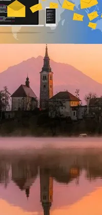 This phone live wallpaper showcases a stunning clock tower resting atop a tranquil lake, with a charming church background amid a scenic Slovenian landscape