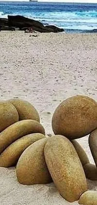 Discover the ultimate beach-inspired live wallpaper for your phone! Featuring a pile of rocks atop a sandy beach, this design draws inspiration from land art to create a stunning, natural look