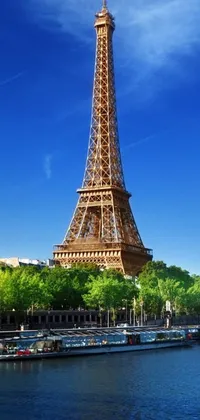 This live phone wallpaper showcases the stunning view of the Eiffel Tower from across the river, set against a sunny day backdrop