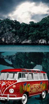 Spruce up your phone screen with this stunning live wallpaper! The red and white vintage bus parked next to a breathtaking water body surrounded by greenery is perfect for every travel enthusiast