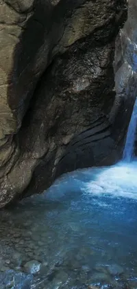 This stunning phone live wallpaper showcases a serene natural scene of a man standing in front of a magnificent waterfall