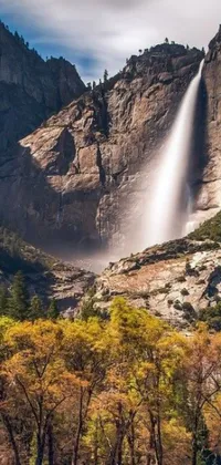 This live phone wallpaper showcases a breathtaking waterfall in the mountains amid autumn foliage