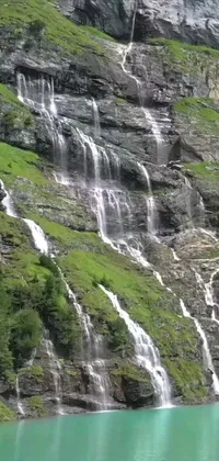 This live wallpaper depicts a group of people standing in front of an awe-inspiring waterfall, set against a hillside