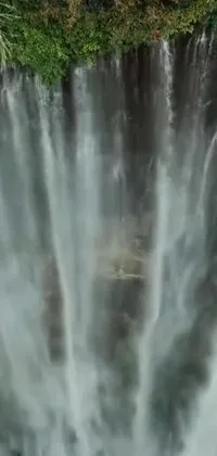 This phone live wallpaper features a stunning view of a waterfall with hurufiyya influenced patterns and Arabic calligraphy integrated into a mesmerizing display of rushing water