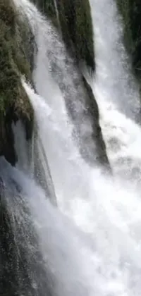 This phone live wallpaper features a stunning hurufiyya-style image of a man in front of an 8-foot fall waterfall