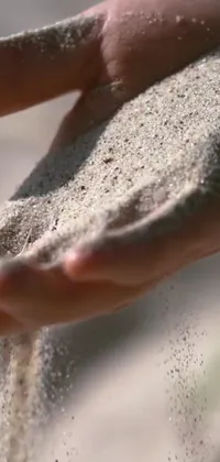 This live wallpaper features a high quality, ultra-detailed, close-up video of a hand holding sand