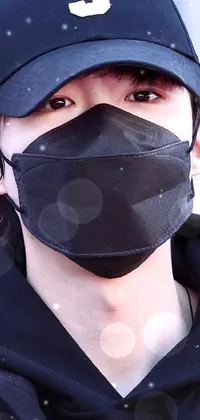 This live wallpaper depicts a close up of a person wearing a face mask, with a dark visor covering the upper part of their face and a medical mask covering the lower part