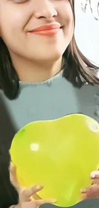This stunning live wallpaper features a cheerful woman holding a bright yellow balloon in a green natural background