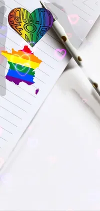 This live wallpaper depicts a white background with a pen resting on a notepad next to a colorful rainbow heart and the words "gay rights"