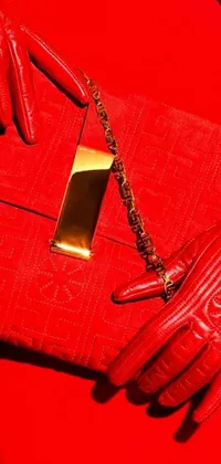 This vibrant and chic live phone wallpaper depicts a red purse placed on top of a red chair