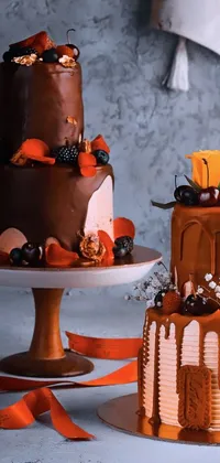 This phone live wallpaper boasts of two luscious cakes sitting atop a table in orange and black tones with a brilliant baroque pattern background