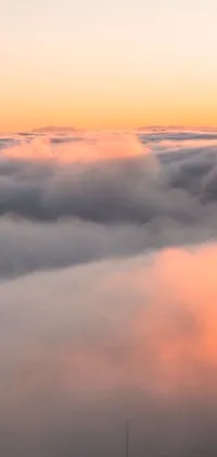 This phone live wallpaper features an aerial view of a misty mountain range at dawn, with the sun rising over the horizon and wispy clouds passing by