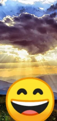 Looking for a fun and cheerful live wallpaper for your phone? Look no further! This yellow smiley face sitting on a green hillside is sure to brighten up your day