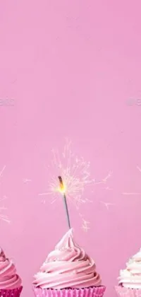 This phone live wallpaper showcases three cupcakes adorned with sparklers, set amidst a lively pink backdrop