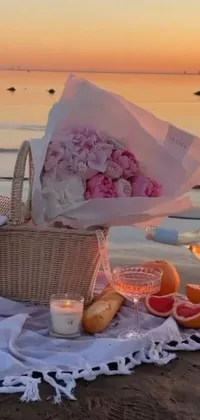 This phone live wallpaper showcases a serene and romantic beachside picnic scene, with a wicker basket filled with delectable treats and an inviting blanket