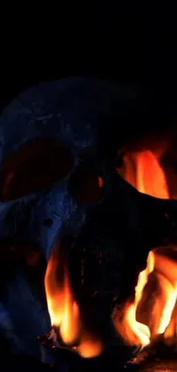 This phone live wallpaper showcases a close up of a blazing fire with a skull at its center