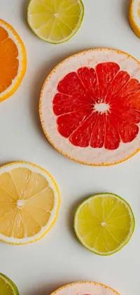 This phone wallpaper features a stunning display of citrus fruits sliced in half and arranged on a white surface, accompanied by scattered oranges and limes