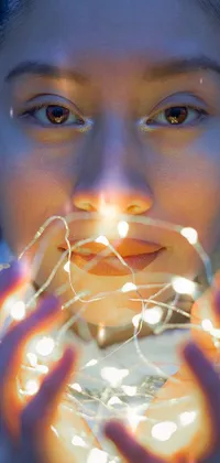 This phone live wallpaper features a close-up shot of a young Asian woman holding a string of lights, creating a gorgeous bokeh effect