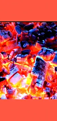 Intensify your phone's screen with a fiery live wallpaper featuring a pile of coal sitting on top of a blazing fire