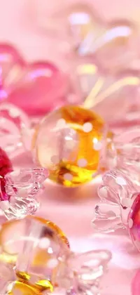 This live phone wallpaper features an exquisite arrangement of glass beads on a table in shimmering hues of yellow and pink