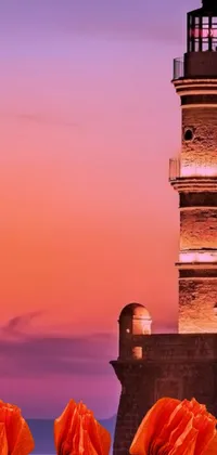 This phone live wallpaper showcases vibrant orange flowers in front of a picturesque lighthouse during a serene pink sunset in Samarkand