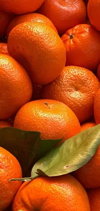 This live wallpaper features a detailed and zoomed in photo of a pile of fresh oranges with leaves on them
