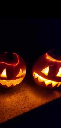 This phone live wallpaper features three intricately carved pumpkins beautifully lit in the dark