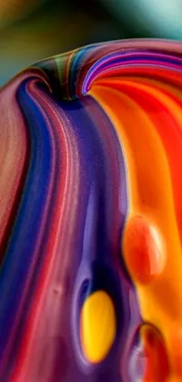This phone live wallpaper features a stunning close-up of a colorful glass art object on a table