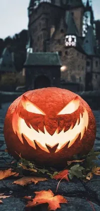 This live wallpaper showcases a Halloween-inspired carved pumpkin with a traditional jack-o-lantern face in the foreground, set against the backdrop of a spooky castle