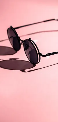 This live wallpaper features a pair of fashionable sunglasses in close-up atop a bright pink surface