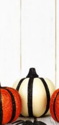This phone live wallpaper captures the essence of autumn with a charming scene of pumpkins on a rustic wooden table adorned with bold black and white stripes