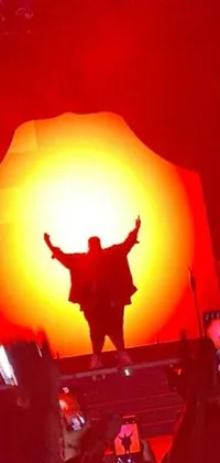 This vibrant live phone wallpaper depicts a man commanding the attention of a lively crowd on a red and orange glowing stage