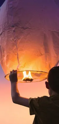 This stunning phone live wallpaper features an enchanting sky lantern, radiating a warm light against the backdrop of a dark, starry sky
