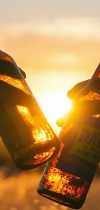 Enhance your phone screen with a stunning live wallpaper featuring two people holding beer bottles under a radiant sunset