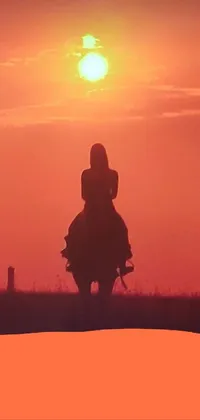 This phone live wallpaper features a gorgeous scene of a female cowgirl riding a horse against a stunning sunset