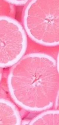 This phone live wallpaper showcases a cluster of colorful grapefruit slices, arranged in layers and topped with a pink neon glow