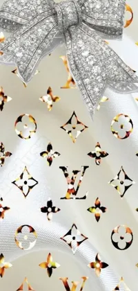 This live wallpaper for phones features a silver bow on a white cloth with a stunning background design inspired by Baroque and Louis Vuitton motifs