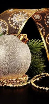 This stunning phone live wallpaper features a close-up shot of a Christmas ornament adorned with gold accessories