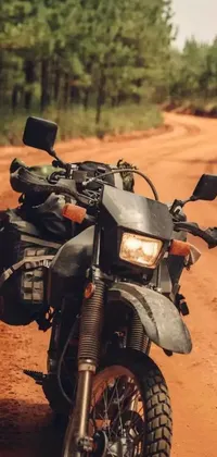 This live wallpaper features an exciting scene of a motorcycle parked on a dirt road in the midst of a forest