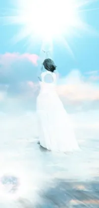 This stunning live phone wallpaper features a beautiful woman in a flowing white dress standing on a sandy beach with crystal clear blue-green ocean waves lapping at her feet