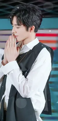 This live wallpaper showcases a captivating man in a pristine white shirt and stylish black vest, captured in a meditative prayer position