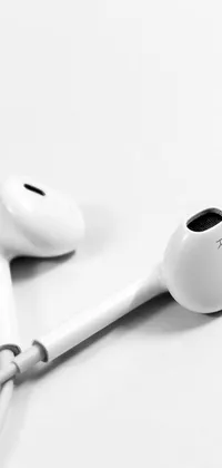 Looking for a sleek and minimalistic live wallpaper for your phone? Look no further than this stunning image featuring a pair of Airpods headphones sitting atop a table
