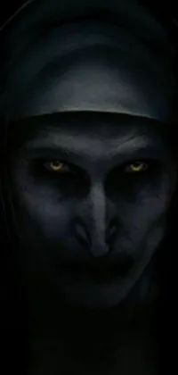 This phone live wallpaper features a frightening image of a nun with yellow eyes lurking in the darkness