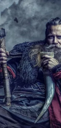 This phone live wallpaper showcases a rugged man in viking clothes, brandishing a knife and standing amidst a snowy landscape with mountains in the background