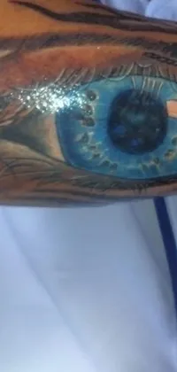 This phone live wallpaper features a captivating blue eye tattoo on an arm, rendered with skillful precision